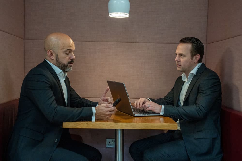 2 businessmen in a booth having a work meeting
