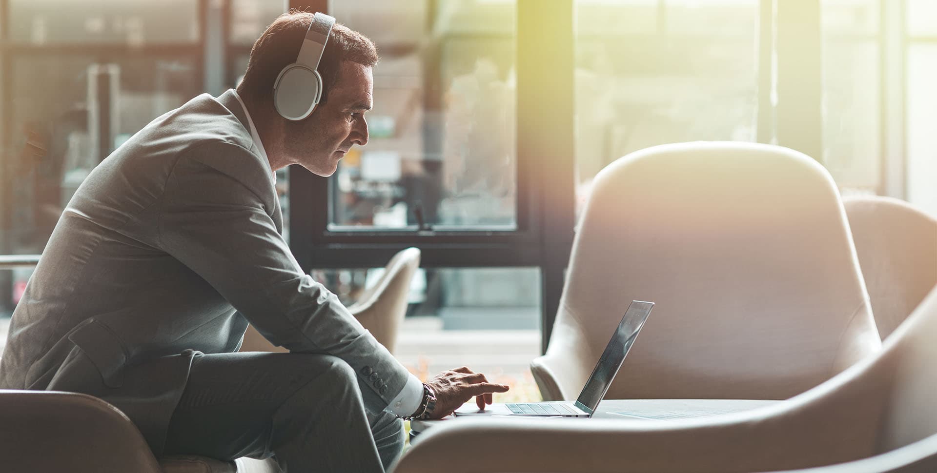 Businessman using his laptop whilst wearing headphones
