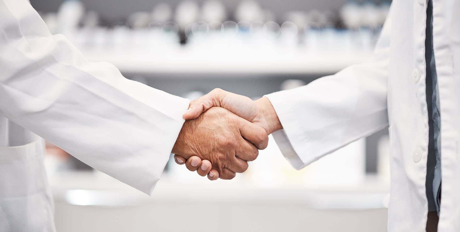 Two pharmacists shaking hands after agreeing on a pharmacy sale